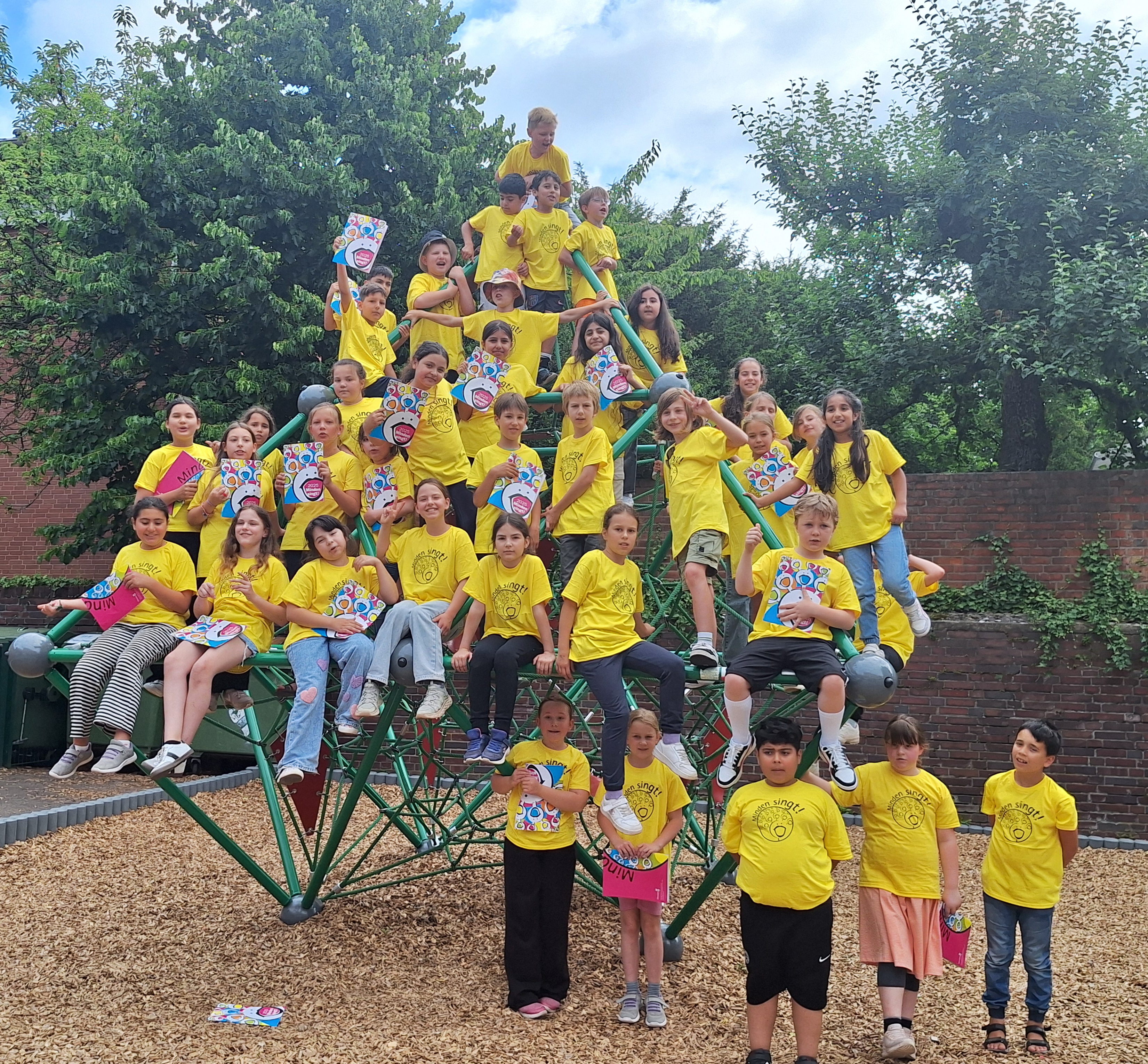 Die Teilnehmenden von "Minden singt!" stehen auf einem Spielgerät auf einem Spielplatz.